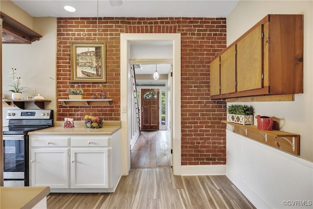 429 4th St, West Point, VA 23181 - kitchen featuring stainless steel electric range, light wood-style floors, light countertops, brick wall, and white cabinetry