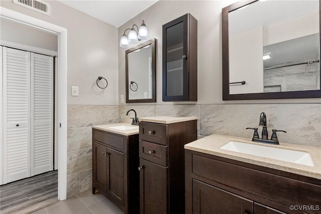 10152 Iron Mill Rd, North Chesterfield, VA 23235 - full bathroom featuring tile walls, a closet, two vanities, tile patterned floors, and wainscoting