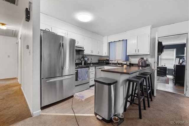 2560 Pin Oak Ct, Colonial Heights, VA 23834 - kitchen featuring appliances with stainless steel finishes, a peninsula, light colored carpet, dark countertops, and under cabinet range hood