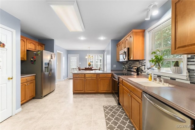 15619 Winding Ash Dr, Chesterfield, VA 23832 - kitchen featuring appliances with stainless steel finishes, a peninsula, brown cabinetry, tasteful backsplash, and recessed lighting