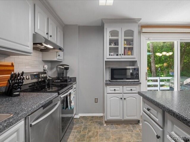 8507 Spruce Pine Dr, North Chesterfield, VA 23235 - kitchen with appliances with stainless steel finishes, under cabinet range hood, dark countertops, backsplash, and glass insert cabinets