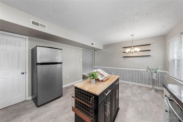 410 Airycrest Dr, Highland Springs, VA 23075 - kitchen featuring freestanding refrigerator, butcher block countertops, dark cabinets, a textured ceiling, and a chandelier