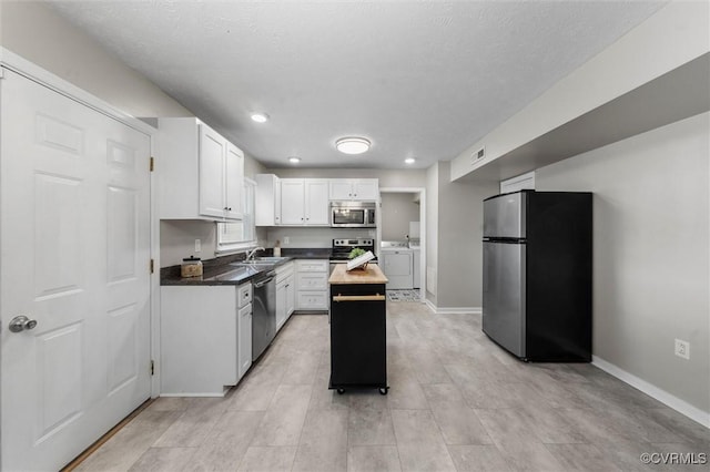 410 Airycrest Dr, Highland Springs, VA 23075 - kitchen featuring appliances with stainless steel finishes, washing machine and dryer, white cabinetry, a kitchen island, and recessed lighting