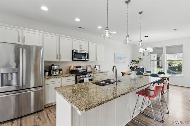 8045 Ellendale Dr, Mechanicsville, VA 23116 - kitchen featuring stainless steel appliances, light wood-style floors, white cabinets, a breakfast bar area, and backsplash