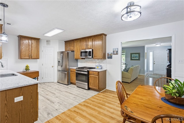 3826 Minitree Glen Dr, Providence Forge, VA 23140 - kitchen with appliances with stainless steel finishes, light wood-style floors, tasteful backsplash, brown cabinetry, and decorative light fixtures