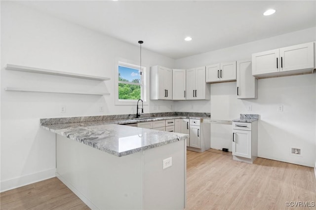 425 Palomino Dr, Louisa, VA 23093 - kitchen with a peninsula, light stone countertops, light wood finished floors, open shelves, and hanging light fixtures