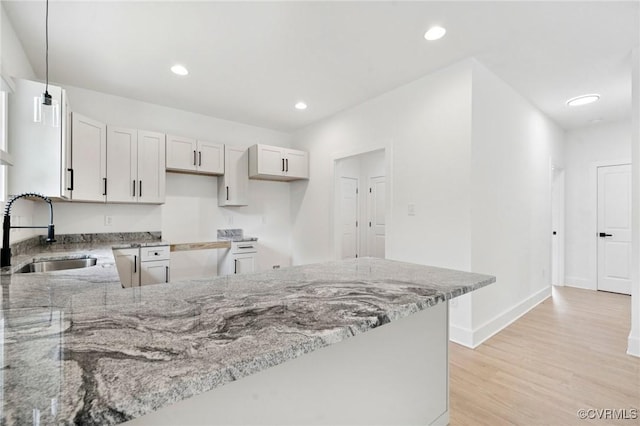 425 Palomino Dr, Louisa, VA 23093 - kitchen with light stone countertops, a peninsula, light wood finished floors, decorative light fixtures, and recessed lighting
