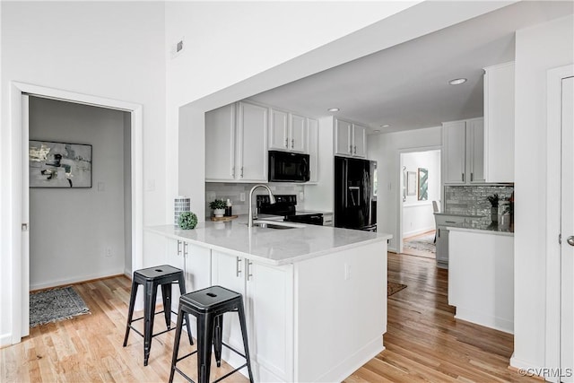 7654 Cherokee Rd, Richmond, VA 23225 - kitchen with black appliances, decorative backsplash, light wood-type flooring, a peninsula, and recessed lighting