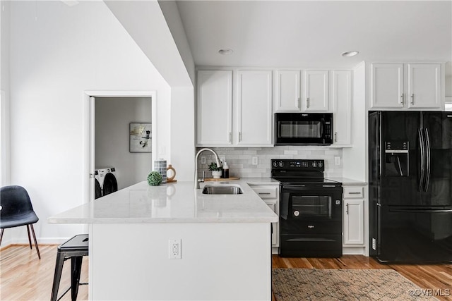 7654 Cherokee Rd, Richmond, VA 23225 - kitchen featuring black appliances, washing machine and dryer, a peninsula, white cabinets, and recessed lighting