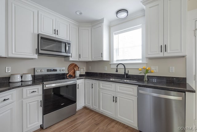 4806 Cutshaw Ave, Richmond, VA 23230 - kitchen with stainless steel appliances, white cabinets, light wood finished floors, dark stone counters, and ornamental molding