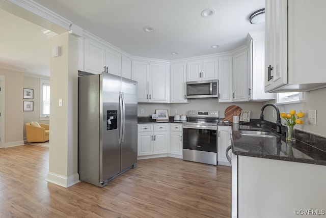 4806 Cutshaw Ave, Richmond, VA 23230 - kitchen featuring appliances with stainless steel finishes, white cabinets, light wood-style flooring, crown molding, and dark stone counters