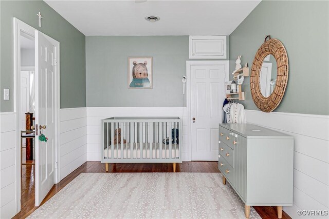 4508 Augusta Ave, Richmond, VA 23230 - bedroom featuring a wainscoted wall, wood finished floors, and a crib
