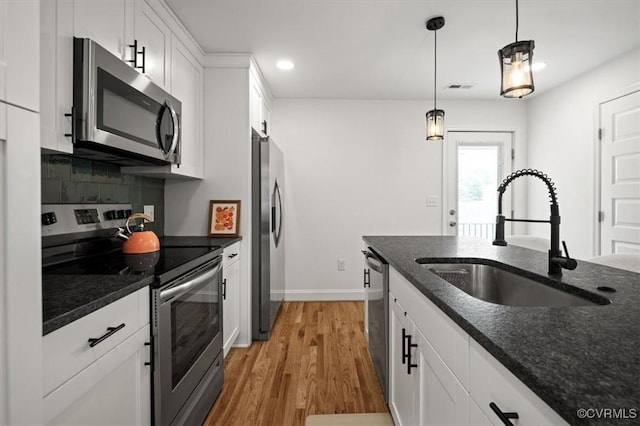 1508 N 29th St, Richmond, VA 23223 - kitchen featuring stainless steel appliances, white cabinetry, light wood-style floors, dark stone countertops, and decorative backsplash
