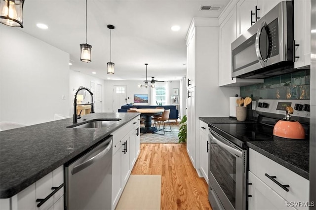 1508 N 29th St, Richmond, VA 23223 - kitchen featuring stainless steel appliances, light wood-style floors, white cabinets, recessed lighting, and hanging light fixtures