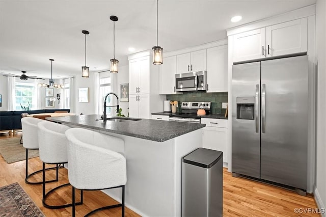 1508 N 29th St, Richmond, VA 23223 - kitchen featuring stainless steel appliances, dark countertops, light wood-type flooring, a breakfast bar, and recessed lighting