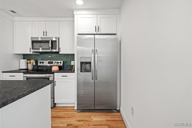 1508 N 29th St, Richmond, VA 23223 - kitchen with appliances with stainless steel finishes, white cabinets, light wood-style flooring, dark countertops, and recessed lighting
