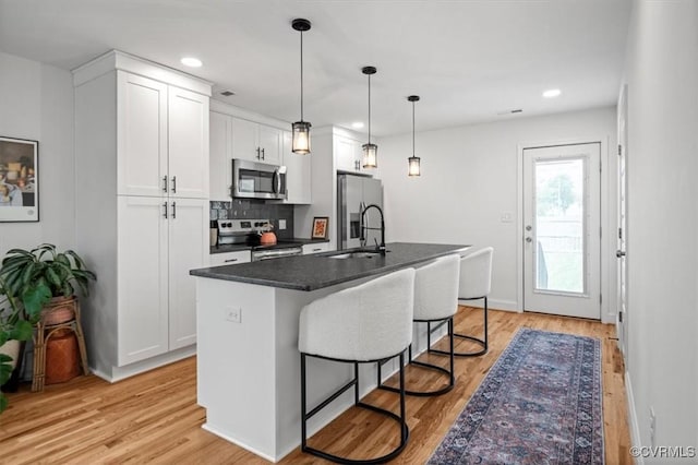 1508 N 29th St, Richmond, VA 23223 - kitchen featuring appliances with stainless steel finishes, light wood-style flooring, a breakfast bar, dark countertops, and recessed lighting