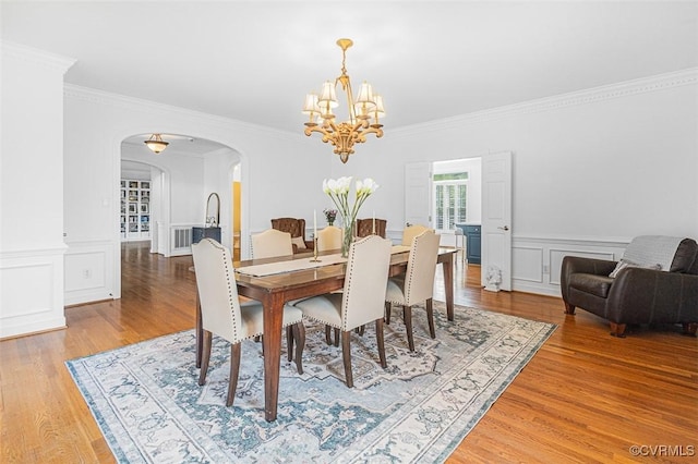 12829 Huntmaster Ln, Henrico, VA 23233 - dining space with a chandelier, arched walkways, light wood-style flooring, ornamental molding, and a decorative wall