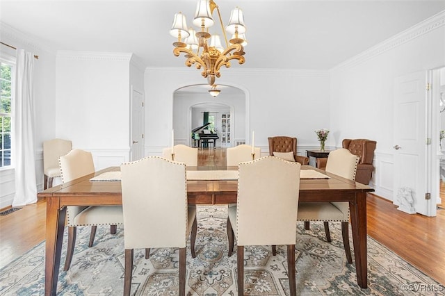 12829 Huntmaster Ln, Henrico, VA 23233 - dining room featuring arched walkways, light wood finished floors, ornamental molding, a chandelier, and a decorative wall