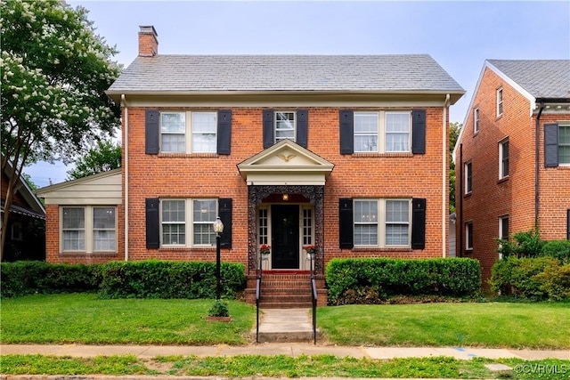 5013 Caledonia Rd, Richmond, VA 23225 - georgian-style home featuring a chimney, brick siding, and a front lawn
