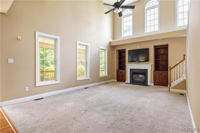706 Colony Oak Ln, Midlothian, VA 23114 - unfurnished living room featuring a towering ceiling, built in shelves, a fireplace with flush hearth, a ceiling fan, and stairway