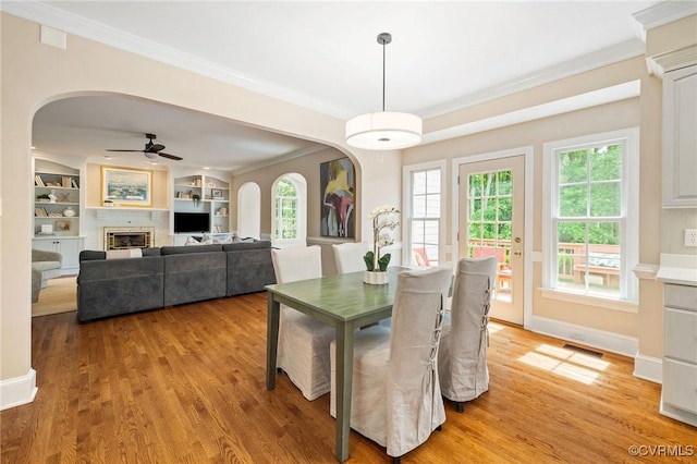 9408 Arrowdel Rd, Henrico, VA 23229 - dining area featuring arched walkways, light wood-style flooring, crown molding, ceiling fan, and a fireplace