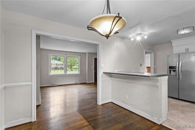 6808 Montauk Dr, Richmond, VA 23225 - kitchen featuring stainless steel fridge with ice dispenser, white cabinets, a peninsula, wood finished floors, and decorative light fixtures