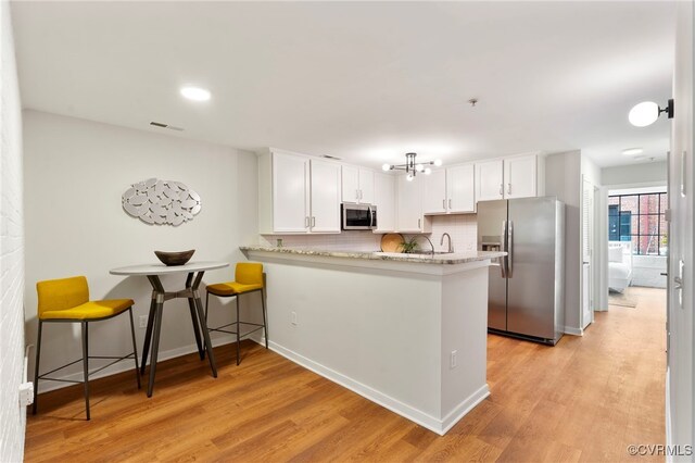 1716 Summit Ave Unit 18, Richmond, VA 23230 - kitchen with stainless steel appliances, light wood-type flooring, white cabinetry, and tasteful backsplash