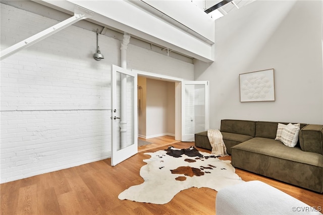 1716 Summit Ave Unit 18, Richmond, VA 23230 - living room featuring brick wall, french doors, a towering ceiling, and wood finished floors