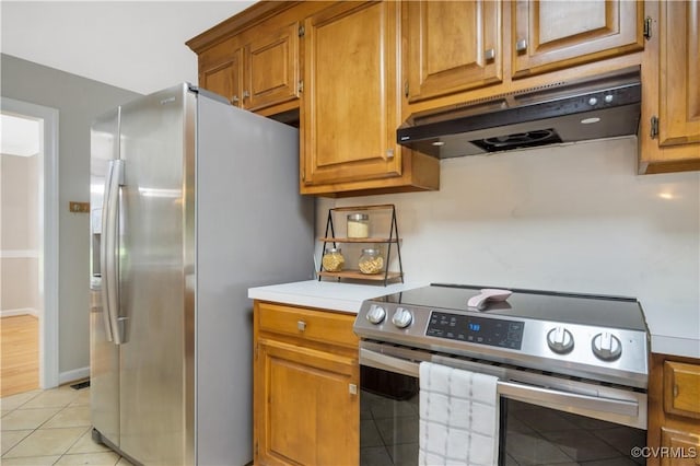 107 Oak Ridge Ct, Williamsburg, VA 23188 - kitchen featuring appliances with stainless steel finishes, under cabinet range hood, brown cabinets, light tile patterned floors, and light countertops