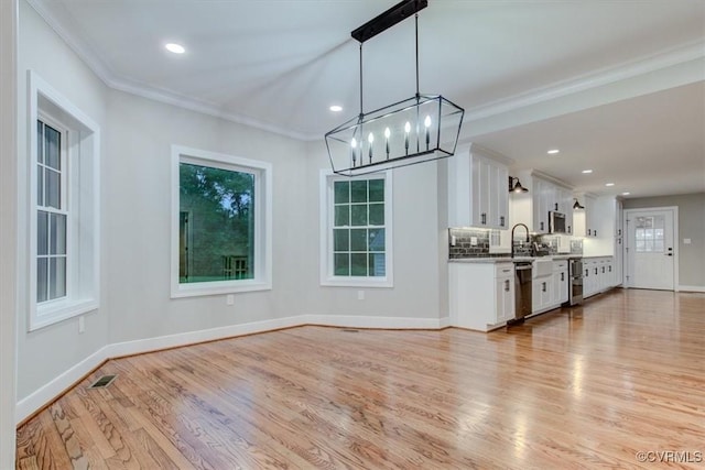 12309 Main St, Stony Creek, VA 23882 - kitchen featuring white cabinetry, light wood-style flooring, appliances with stainless steel finishes, a chandelier, and crown molding
