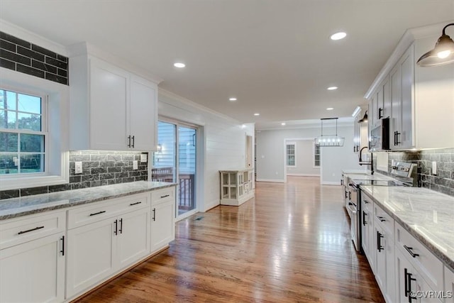 12309 Main St, Stony Creek, VA 23882 - kitchen with stainless steel appliances, healthy amount of natural light, white cabinets, decorative backsplash, and ornamental molding