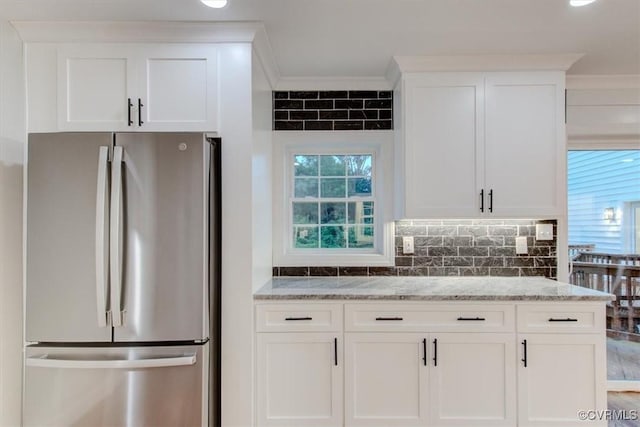 12309 Main St, Stony Creek, VA 23882 - kitchen with freestanding refrigerator, light stone counters, crown molding, white cabinetry, and tasteful backsplash