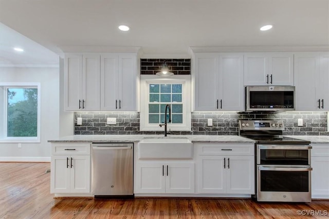 12309 Main St, Stony Creek, VA 23882 - kitchen featuring stainless steel appliances, light stone countertops, white cabinetry, decorative backsplash, and light wood-style floors