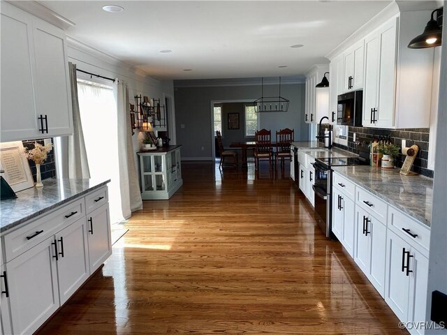 12309 Main St, Stony Creek, VA 23882 - kitchen with black microwave, range with electric stovetop, white cabinetry, decorative backsplash, and crown molding