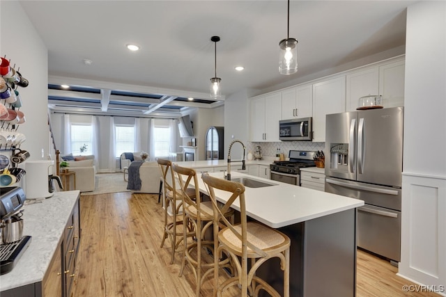 6504 Sanford Springs Cv, Midlothian, VA 23112 - kitchen featuring stainless steel appliances, light countertops, white cabinetry, a breakfast bar area, and light wood finished floors