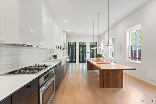 2417 E Grace St, Richmond, VA 23223 - kitchen with stainless steel appliances, wooden counters, a center island, backsplash, and light wood-style floors