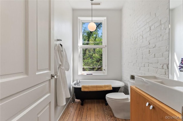 2417 E Grace St, Richmond, VA 23223 - bathroom featuring a soaking tub, vanity, and hardwood / wood-style floors