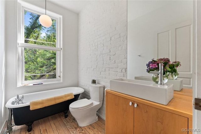 2417 E Grace St, Richmond, VA 23223 - bathroom with a soaking tub, vanity, and wood finished floors