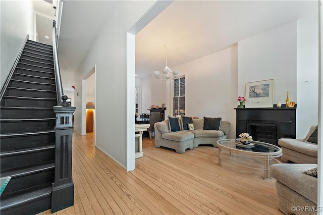 2417 E Grace St, Richmond, VA 23223 - living room featuring a chandelier, light wood-style flooring, stairway, and a fireplace