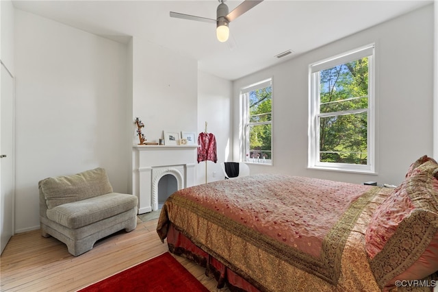 2417 E Grace St, Richmond, VA 23223 - bedroom with wood-type flooring, a ceiling fan, and a fireplace