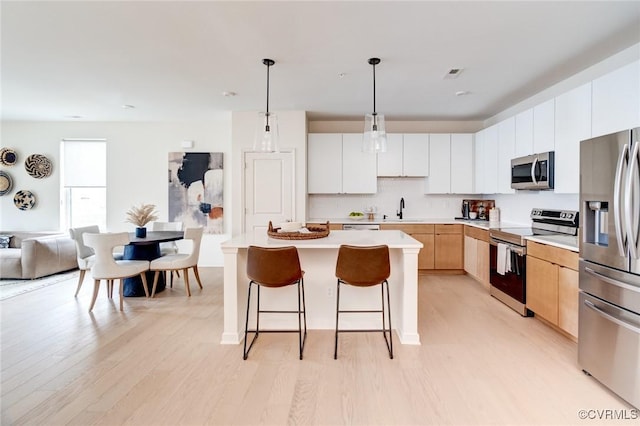 3446 Carlton St Unit 6-8A, Richmond, VA 23230 - kitchen with appliances with stainless steel finishes, a breakfast bar, light countertops, and light wood-type flooring