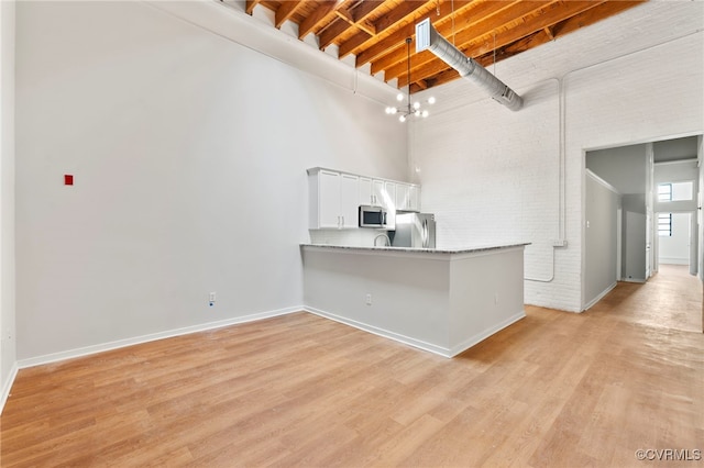1716 Summit Ave Unit 14, Richmond, VA 23230 - kitchen with appliances with stainless steel finishes, a towering ceiling, light wood finished floors, white cabinetry, and beam ceiling