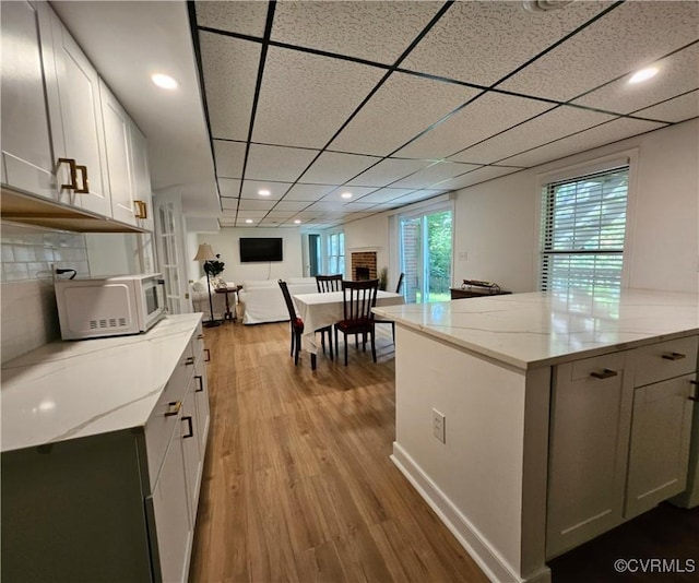 10278 Henderson Hall Rd, Mechanicsville, VA 20116 - kitchen featuring white microwave, wood finished floors, open floor plan, light stone countertops, and tasteful backsplash