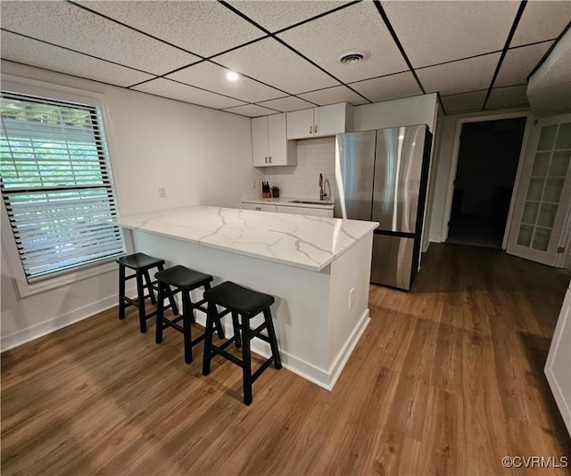 10278 Henderson Hall Rd, Mechanicsville, VA 20116 - kitchen with freestanding refrigerator, a breakfast bar, white cabinetry, wood finished floors, and a peninsula