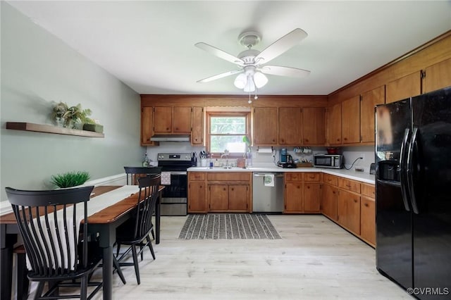 2000 Point Of Rocks Rd, Chester, VA 23836 - kitchen with stainless steel appliances, under cabinet range hood, brown cabinetry, light wood-style floors, and ceiling fan