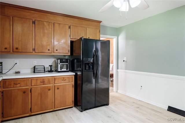 2000 Point Of Rocks Rd, Chester, VA 23836 - kitchen featuring black fridge with ice dispenser, brown cabinets, light wood-style floors, ceiling fan, and wainscoting