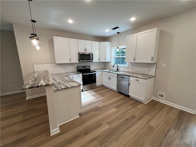 8104 Strath Rd, Henrico, VA 23231 - kitchen with appliances with stainless steel finishes, a peninsula, white cabinetry, light stone countertops, and light wood finished floors