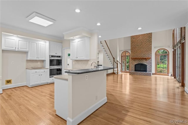 9261 Royal Grant Dr, Hanover, VA 23116 - kitchen with stainless steel double oven, a peninsula, light wood-type flooring, open floor plan, and white cabinets