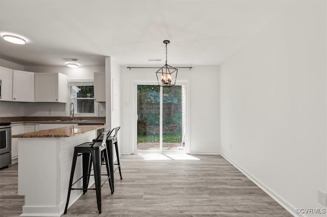15241 Broadwater Cir, Chesterfield, VA 23831 - kitchen featuring a breakfast bar area, white cabinetry, light wood-type flooring, and hanging light fixtures